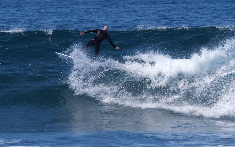 Der Surfer steuert sein Board hinter die Welle